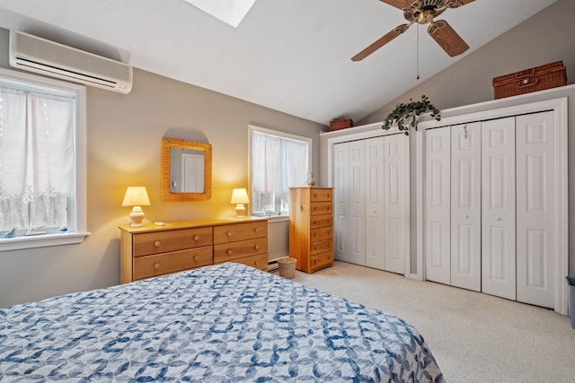 bedroom with carpet, multiple closets, lofted ceiling with skylight, a ceiling fan, and a wall mounted air conditioner