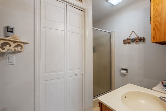 bathroom with a shower with door, a closet, a sink, and a textured ceiling