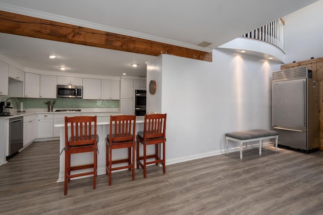 kitchen featuring stainless steel appliances, light countertops, backsplash, and dark wood-type flooring