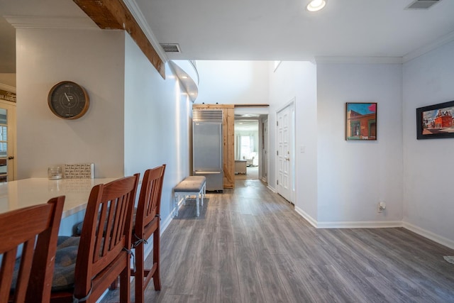 hallway featuring visible vents, crown molding, baseboards, and wood finished floors