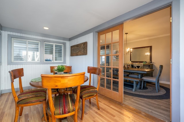 dining space featuring light wood-type flooring, crown molding, baseboards, and a notable chandelier