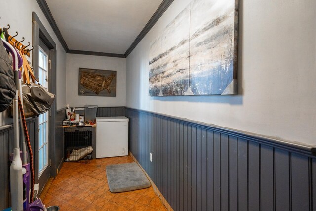 interior space with a wainscoted wall, tile patterned flooring, and crown molding