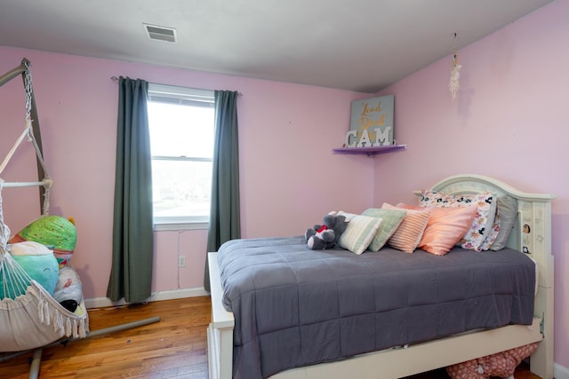 bedroom with visible vents, baseboards, and wood finished floors