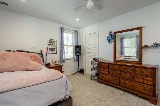 bedroom with baseboards, visible vents, light colored carpet, ceiling fan, and a closet