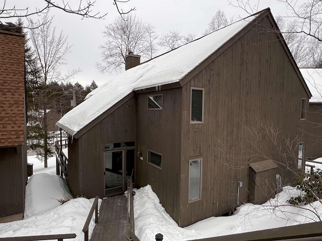 view of snow covered exterior featuring a chimney