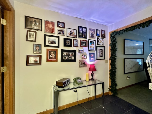 hallway featuring dark tile patterned flooring and baseboards