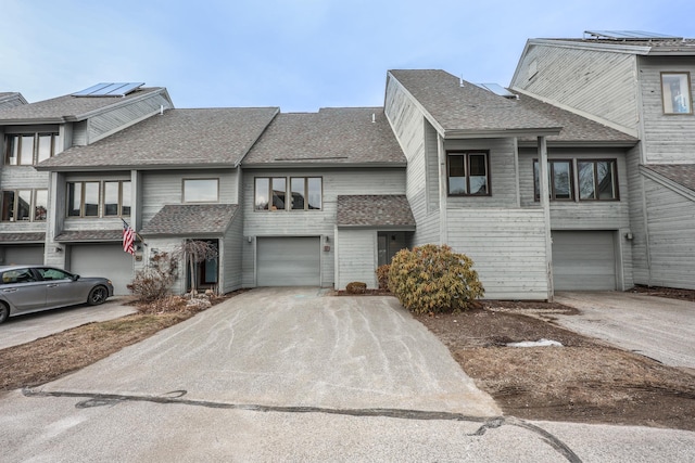 townhome / multi-family property featuring concrete driveway, a shingled roof, and an attached garage