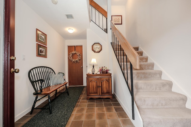 entryway featuring baseboards, stairs, visible vents, and dark tile patterned flooring