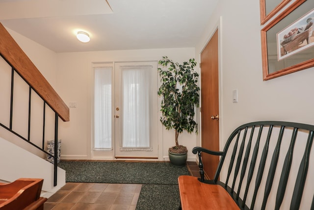 tiled foyer featuring stairs and baseboards