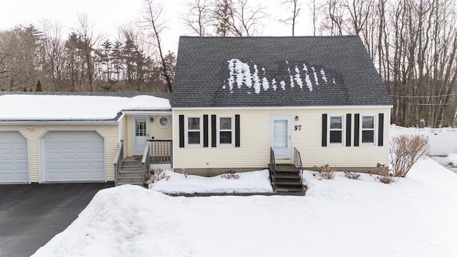 cape cod-style house featuring a shingled roof, driveway, and an attached garage