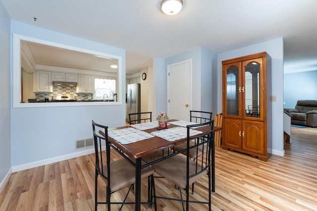 dining space with light wood-style floors, visible vents, and baseboards