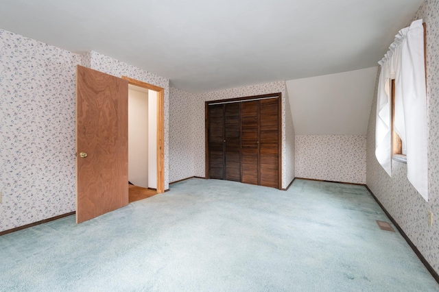 interior space with baseboards, carpet floors, a closet, and wallpapered walls