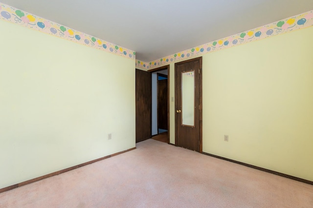 empty room featuring light carpet and baseboards