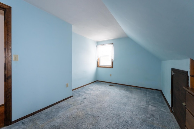 additional living space with carpet floors, vaulted ceiling, and baseboards