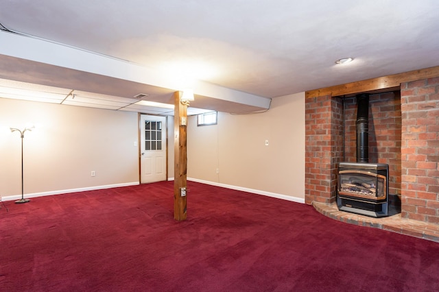 finished below grade area featuring carpet floors, a wood stove, and baseboards