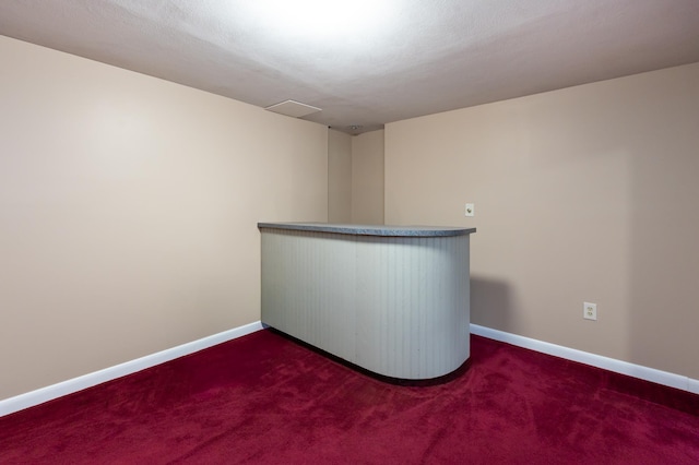 spare room with baseboards and dark carpet