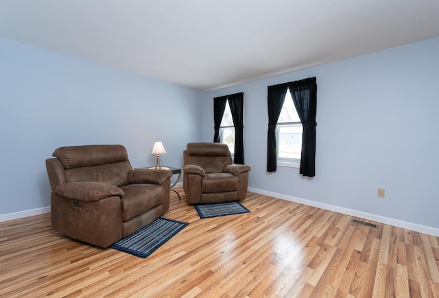 living room featuring wood finished floors, visible vents, and baseboards