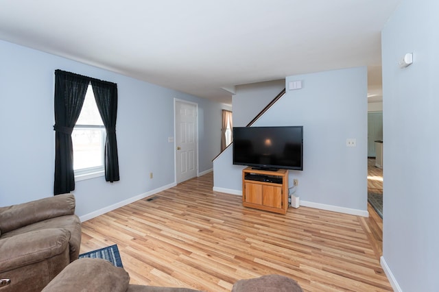 unfurnished living room featuring baseboards, visible vents, and light wood-style floors