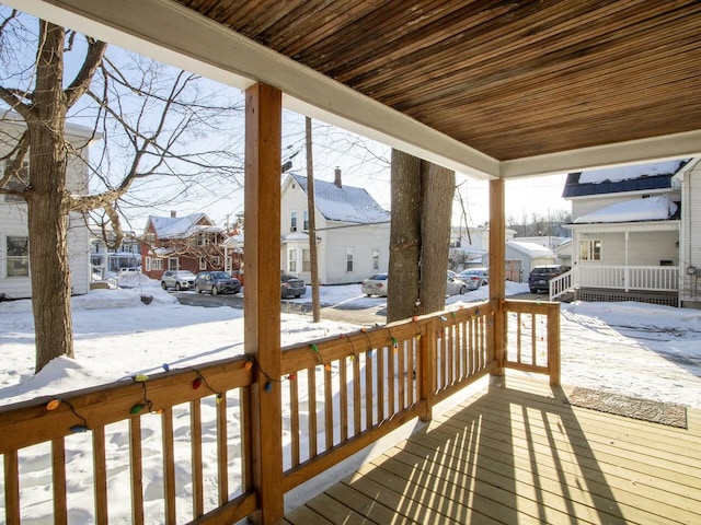 snow covered deck with a residential view and covered porch