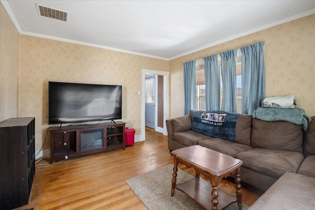 living area featuring light wood-style flooring, visible vents, baseboards, ornamental molding, and wallpapered walls