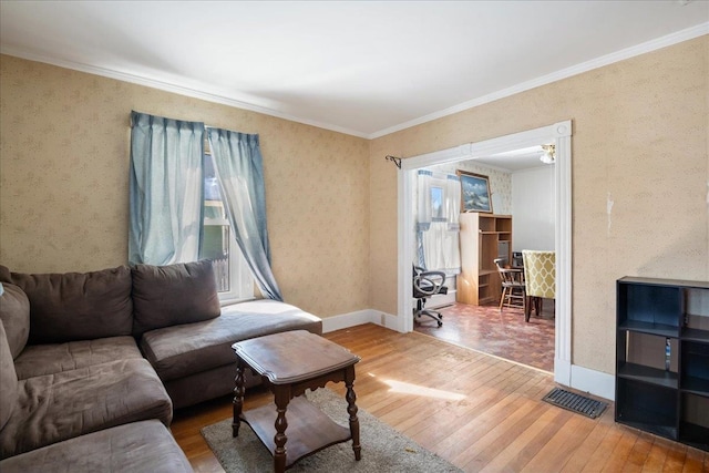 living area featuring hardwood / wood-style flooring, baseboards, wallpapered walls, and ornamental molding