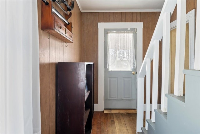 doorway to outside with wooden walls, hardwood / wood-style floors, stairway, and crown molding