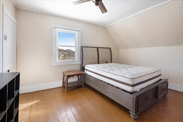 bedroom featuring wood-type flooring, ceiling fan, vaulted ceiling, baseboards, and wallpapered walls