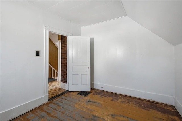 spare room with vaulted ceiling, stairway, wood-type flooring, and baseboards