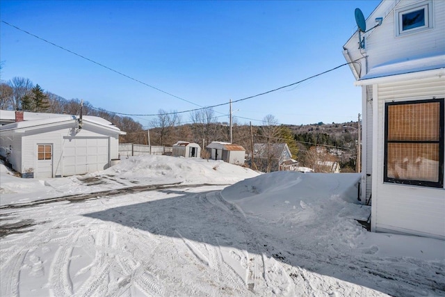 yard layered in snow with a garage and an outdoor structure