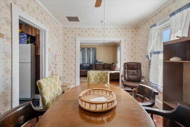 dining space with crown molding, plenty of natural light, visible vents, and wallpapered walls