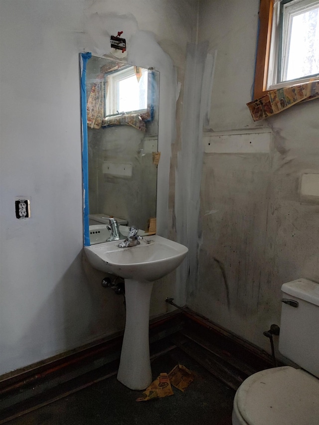 bathroom featuring curtained shower, toilet, and a healthy amount of sunlight