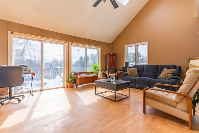 living area featuring light wood finished floors, plenty of natural light, high vaulted ceiling, and a ceiling fan