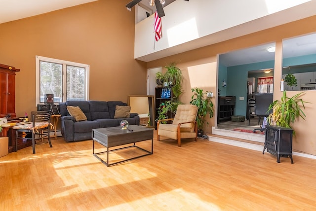 living area with high vaulted ceiling, a ceiling fan, and wood finished floors