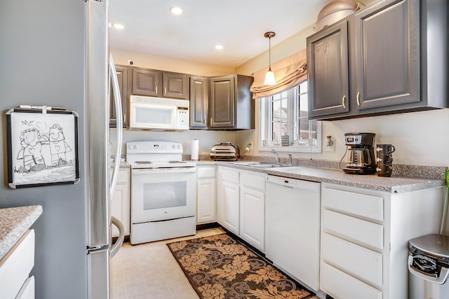 kitchen featuring recessed lighting, white appliances, a sink, hanging light fixtures, and light countertops