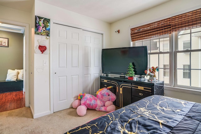 carpeted bedroom with a closet and baseboards