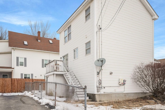 view of snow covered exterior with stairs and fence