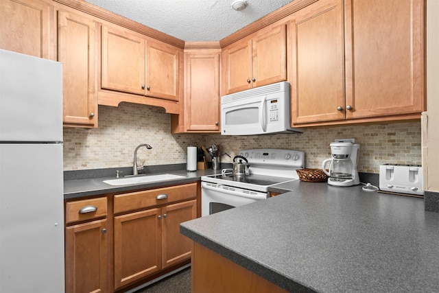 kitchen featuring dark countertops, white appliances, backsplash, and a sink