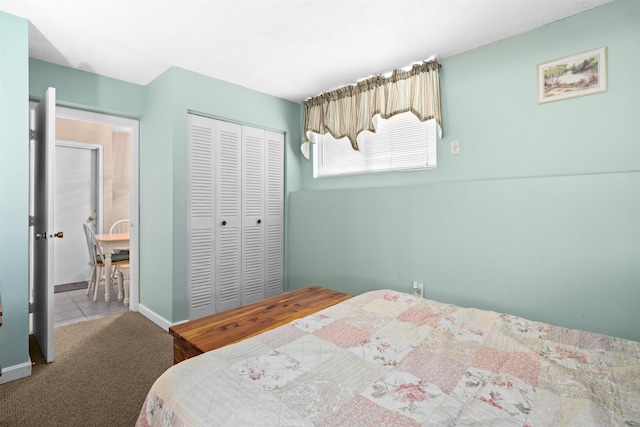 carpeted bedroom featuring tile patterned flooring, a closet, and baseboards