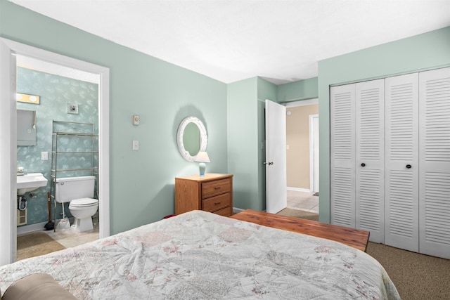 bedroom with a closet, baseboards, connected bathroom, and a sink