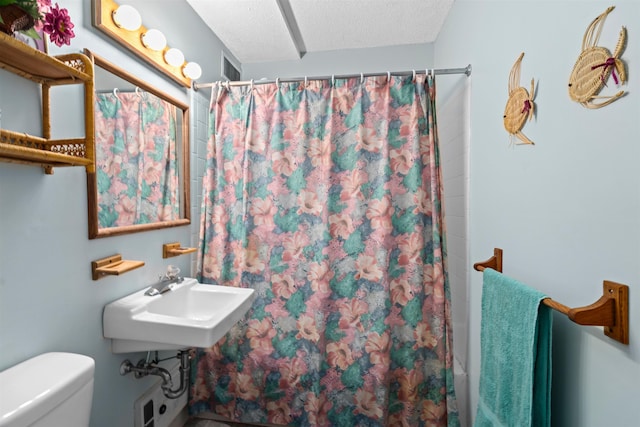 bathroom featuring a shower with curtain, a sink, a textured ceiling, and toilet