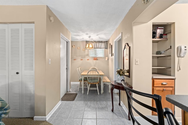 dining room with a textured ceiling, baseboards, and light tile patterned floors