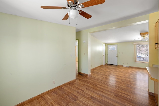 spare room featuring wood finished floors, visible vents, and baseboards