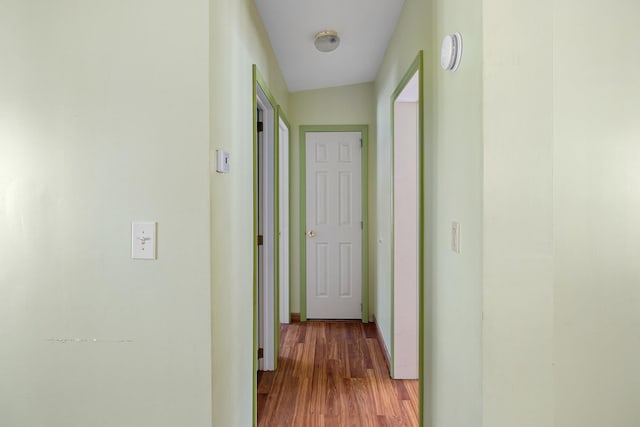 corridor featuring wood finished floors and baseboards