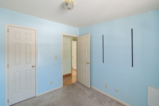 unfurnished bedroom featuring light colored carpet and baseboards