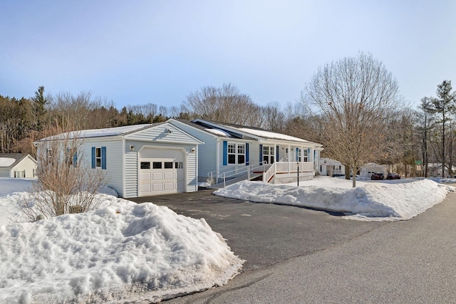 view of front facade featuring an attached garage, driveway, and solar panels