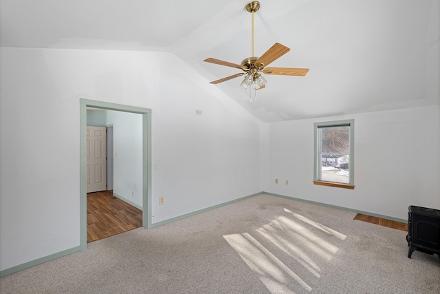 bonus room featuring baseboards, a ceiling fan, lofted ceiling, a wood stove, and carpet