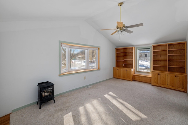 interior space featuring lofted ceiling, a ceiling fan, a wood stove, and baseboards