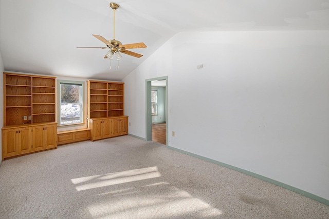 unfurnished living room with lofted ceiling, ceiling fan, baseboards, and light colored carpet