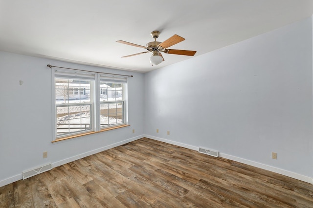 empty room featuring wood finished floors, visible vents, and baseboards