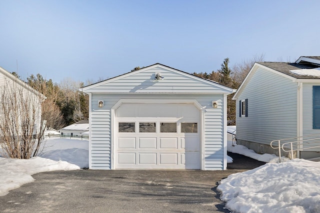 snow covered garage featuring a garage and driveway